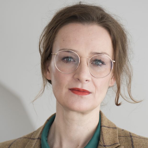 Auf dem Foto ist die Publizistin Franziska Schutzbach zu sehen, sie trägt eine flaschengrüne Bluse und einen karierten Blazer.